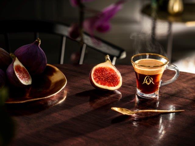 Glass cup of L'OR coffee with a fig fruit on a table